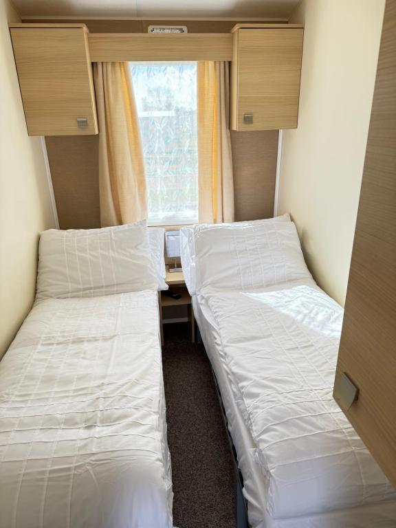 due letti in una piccola stanza con una finestra di Sweet caravan close to beach a Great Yarmouth