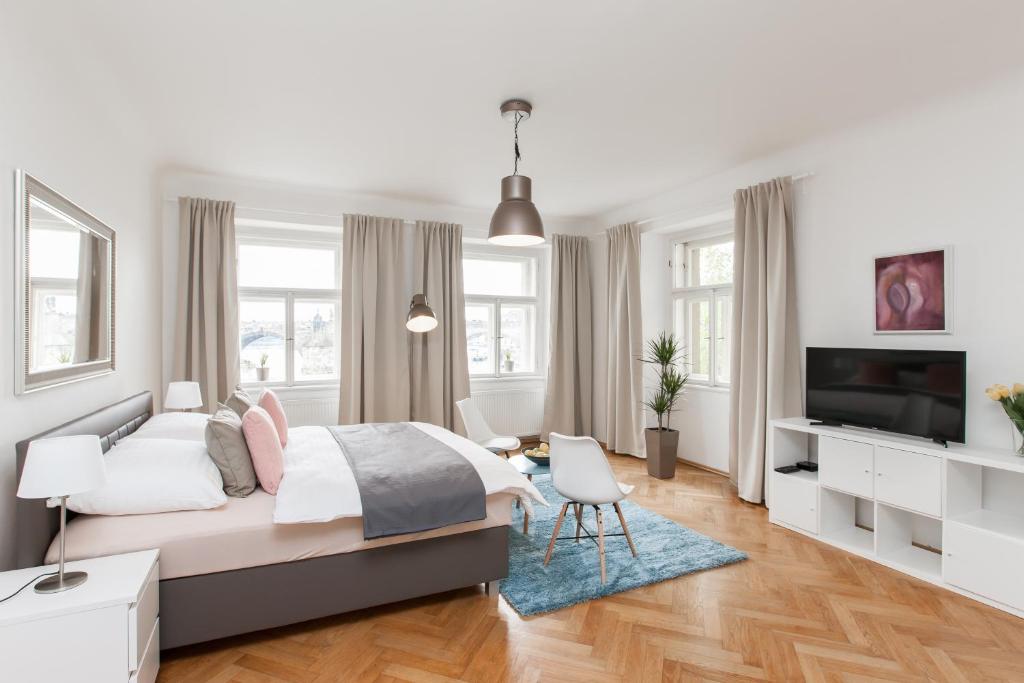 a white bedroom with a bed and a tv at Prague Historic Center Apartments in Prague