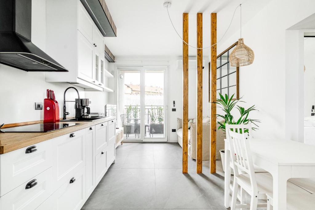 a kitchen with white cabinets and a white table at Certosa District - Modern Flat & Free Box Parking in Milan