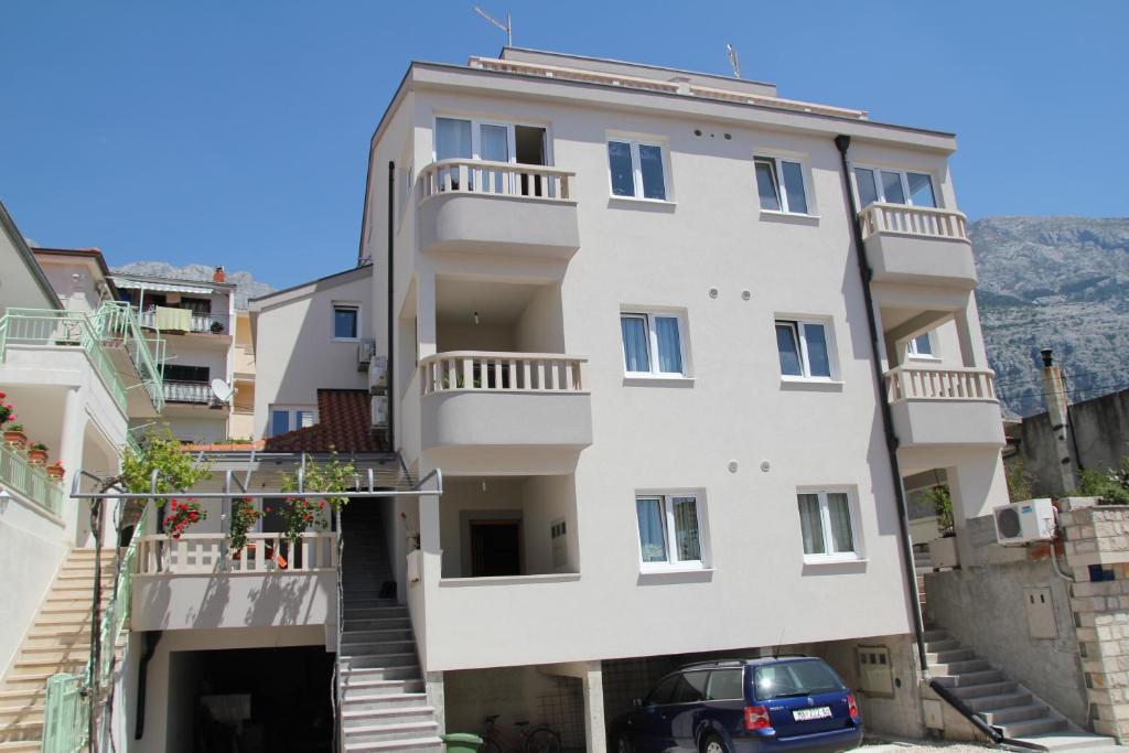 a white building with a car parked in front at Apartments Filipovic in Makarska