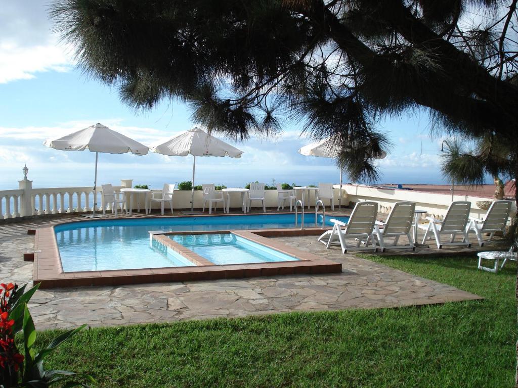 - une piscine avec chaises longues et parasols et l'océan dans l'établissement Finca AliBaba, à Santa Úrsula