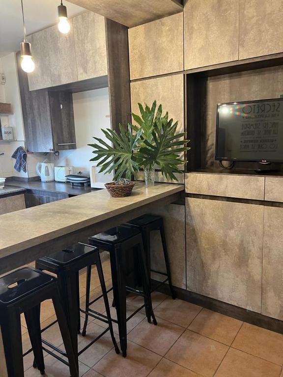 a kitchen with a counter with stools and a tv at Monoambiente en complejo privado con Piscina en microcentro - Excelente Ubicacion in San Juan