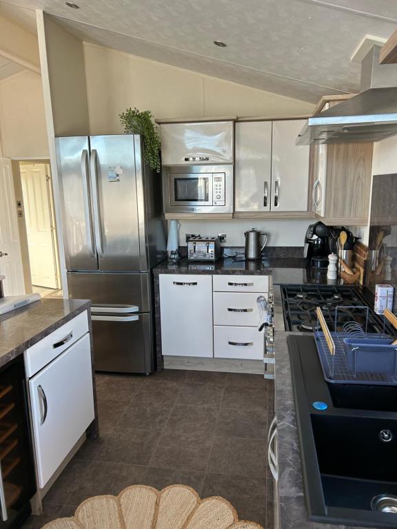 a kitchen with white cabinets and a stainless steel refrigerator at Kent Getaways in Westgate-on-Sea