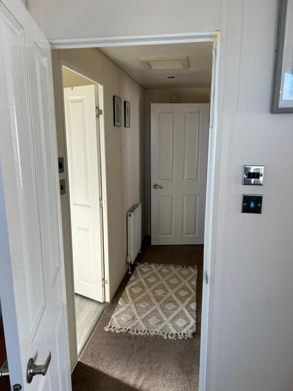 a hallway with a white door and a rug at Kent Getaways in Westgate-on-Sea