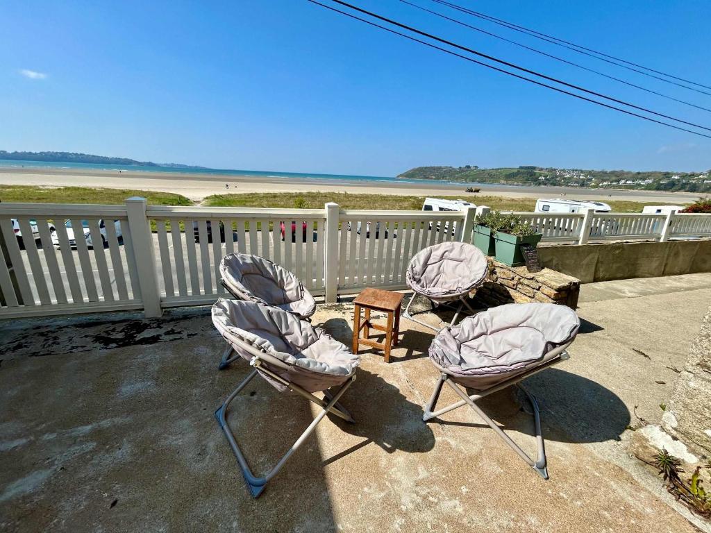 - trois chaises et une table sur une terrasse couverte donnant sur la plage dans l'établissement Charming seaside family home - sleeps 8, à Saint-Michel-en-Grève