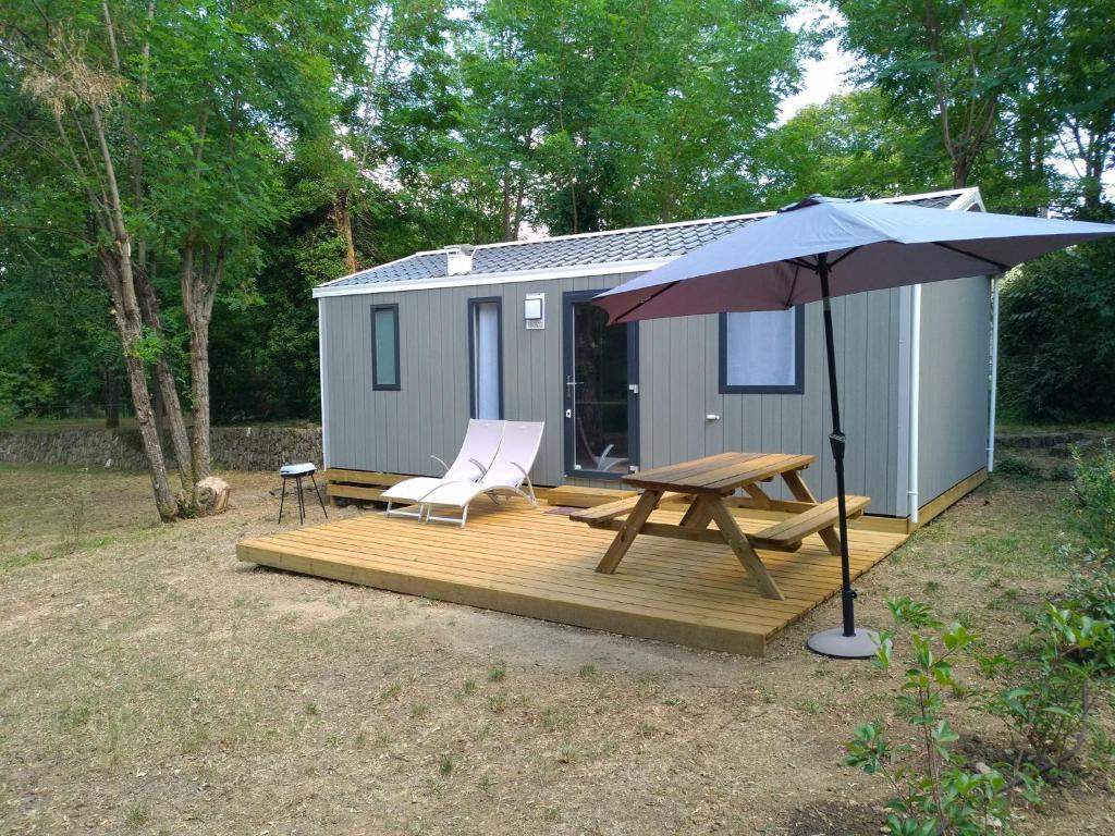 a cabin with a picnic table and an umbrella at Camping le mas du serre in Gravières
