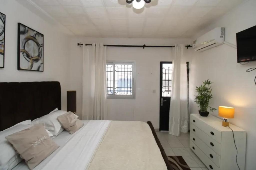 a bedroom with a large white bed and a window at RJS Appart Homey1 avec Jacuzzi in Douala