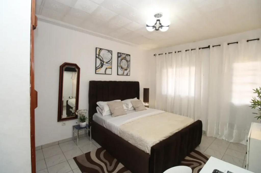 a bedroom with a large bed and a mirror at RJS Appart Homey1 avec Jacuzzi in Douala