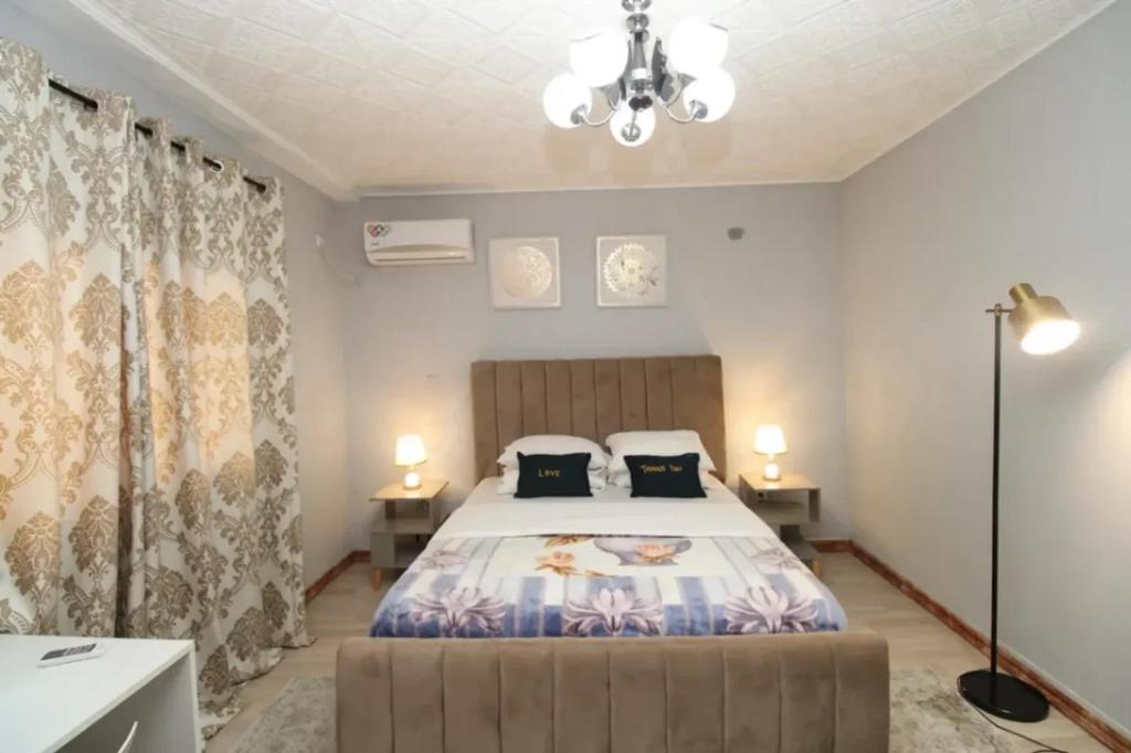 a bedroom with a large bed and two lamps at RJS Appart Homey1 avec Jacuzzi in Douala