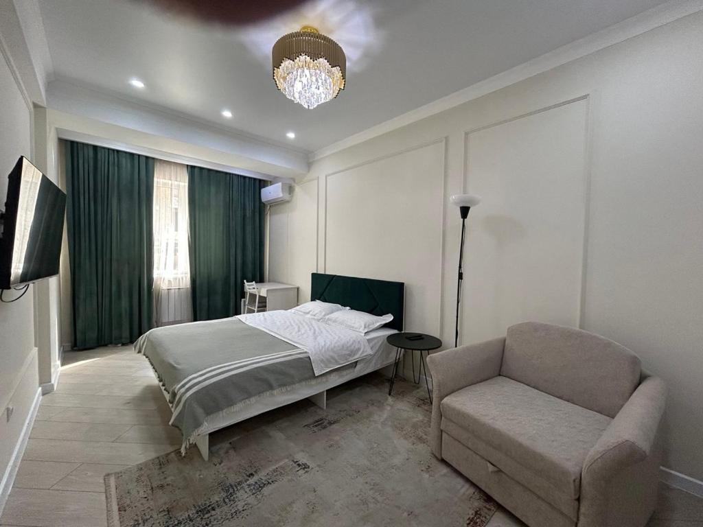 a bedroom with a bed and a chair and a chandelier at AURA on Jumabek street 233 in Bishkek