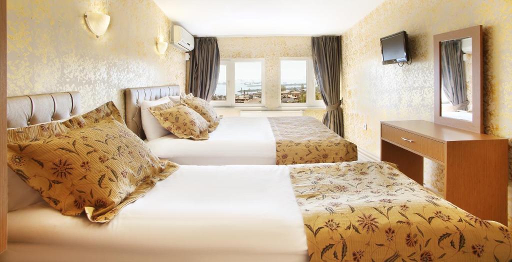 a hotel room with two beds and a mirror at Theodian Hotel in Istanbul