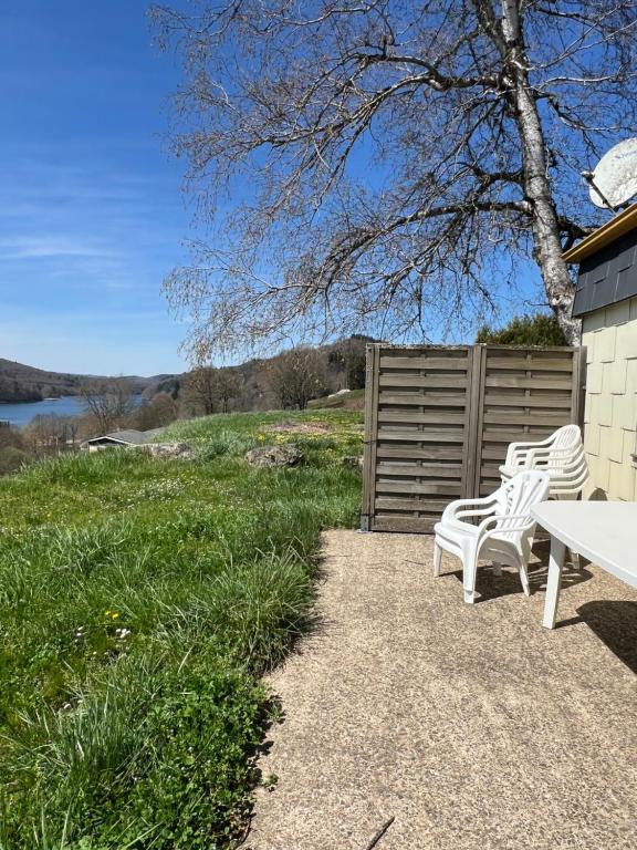 - 2 chaises blanches et une table sur la terrasse dans l'établissement Appartement 7 personnes base de loisirs des Bouldouires, à La Salvetat-sur-Agout