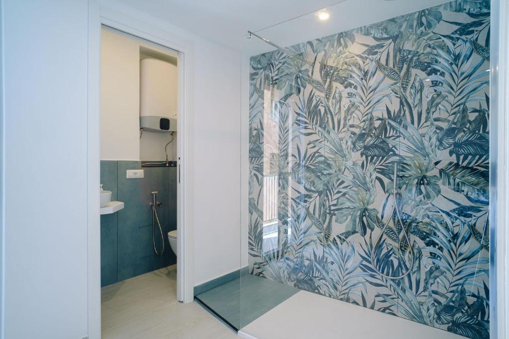 baño con papel pintado de color azul y blanco en BED INN - Palazzo Urbe, en Olbia