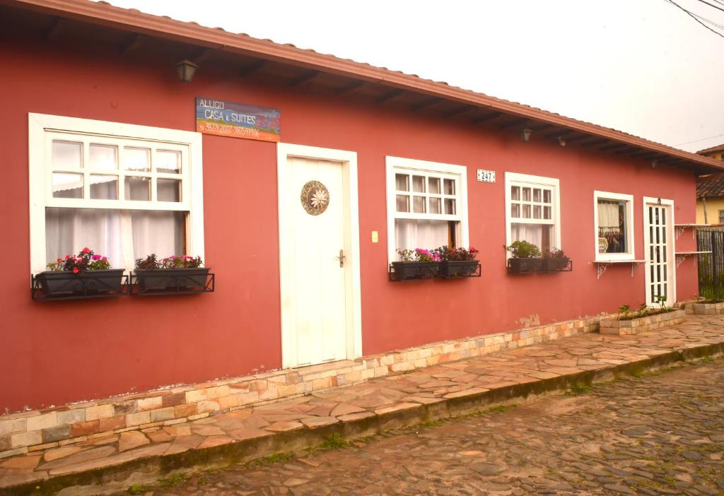 a red building with windows and flower boxes at Suítes e Loft do Tião in Lavras Novas