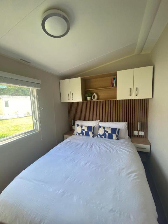 a bedroom with a large white bed with a window at Pebbles Romney Sands in Greatstone