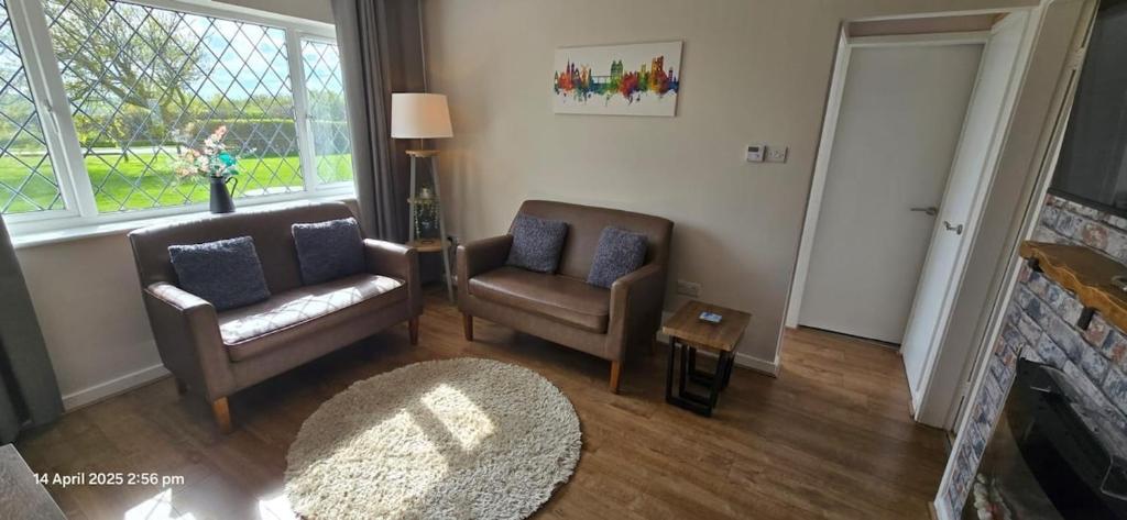 a living room with two chairs and a fireplace at Cozy Nook in Gristhorpe