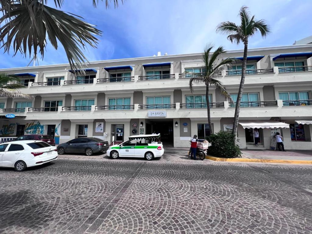 un edificio con coches aparcados delante en Hotel La Siesta Malecón, en Mazatlán