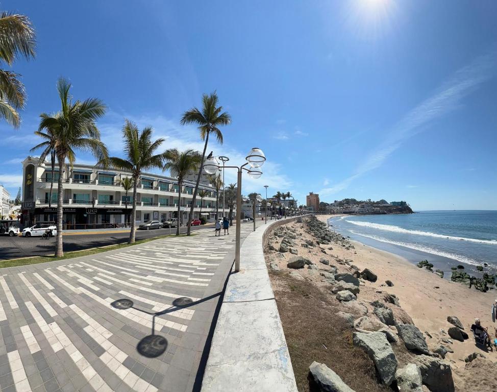 Una playa con palmeras y un edificio y el océano. en Hotel La Siesta Malecón, en Mazatlán