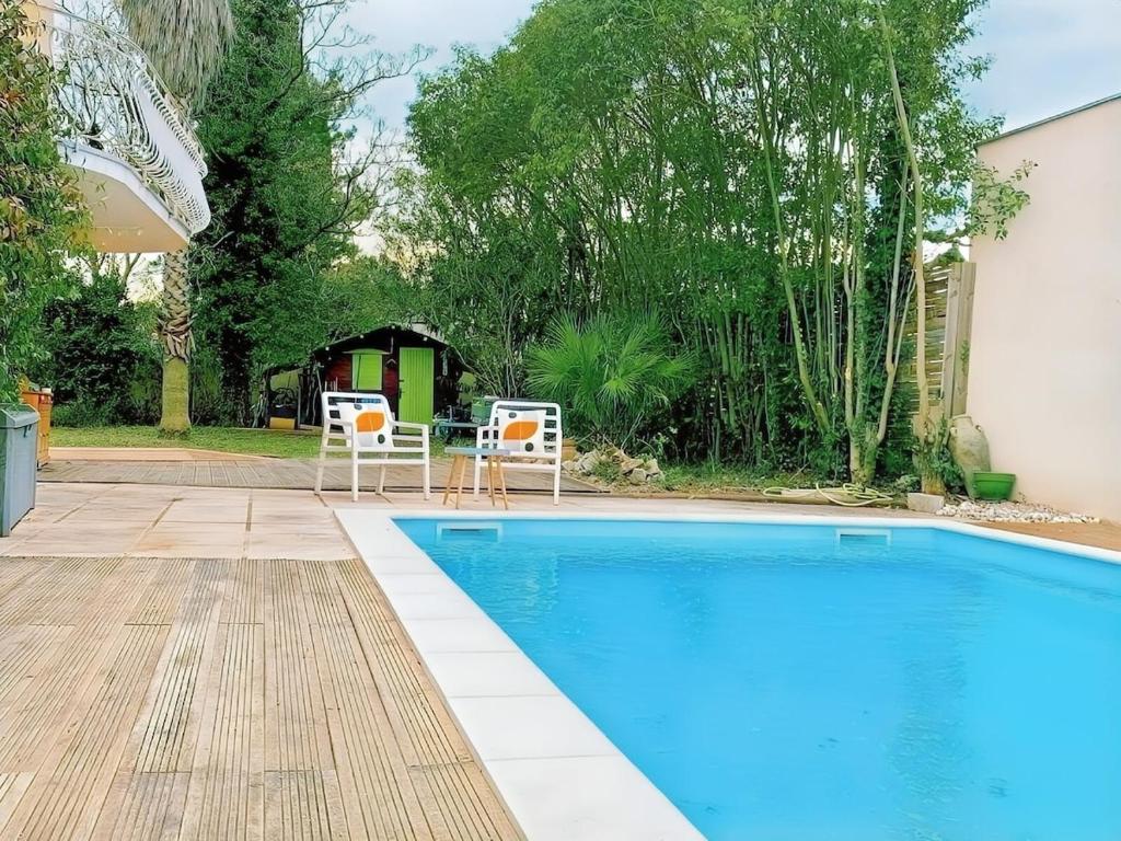 - une piscine avec 2 chaises et une table ainsi qu'une maison dans l'établissement South of France Villa Family Home, à Vendargues