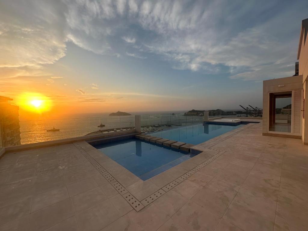 two swimming pools on a building with the sunset in the background at Luxurious Apartment with Ocean View in Santa Marta