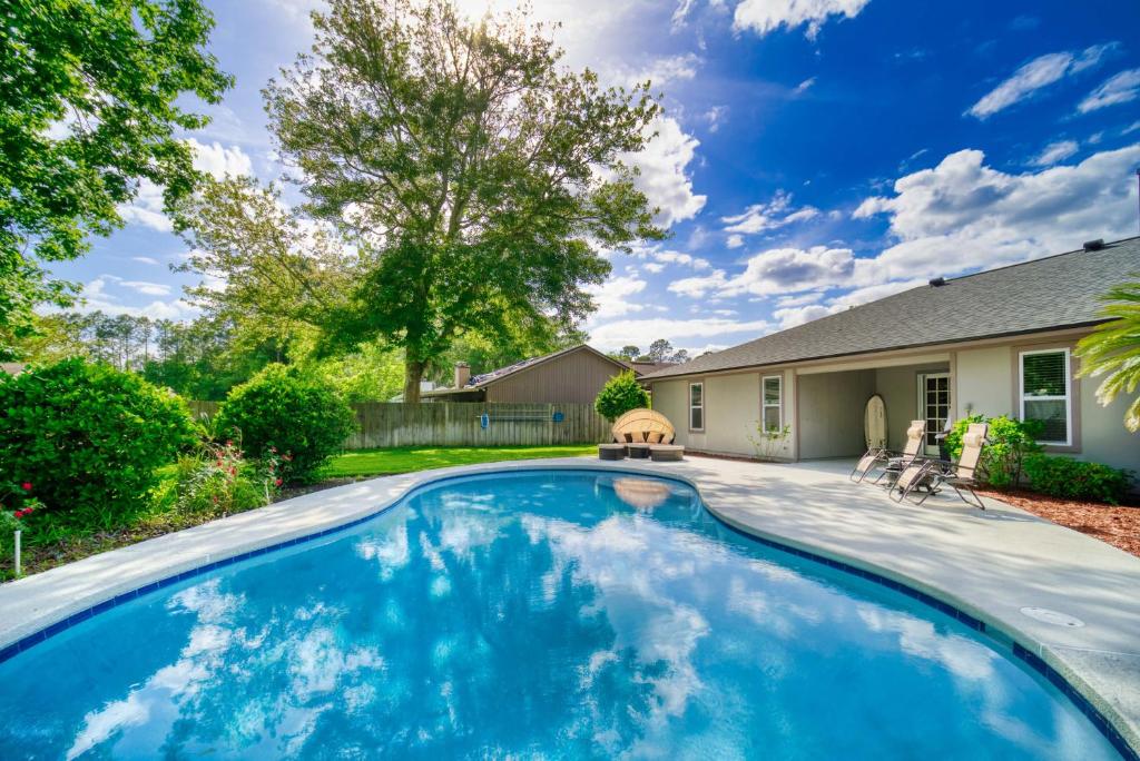 a swimming pool in the backyard of a home with a house at Private Heated Pool Arcade Games Sleeps 10 Jacksonville Home in Jacksonville