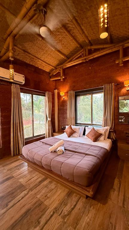 a large bed in a room with windows at Kashid Boutique Resort in Sarne