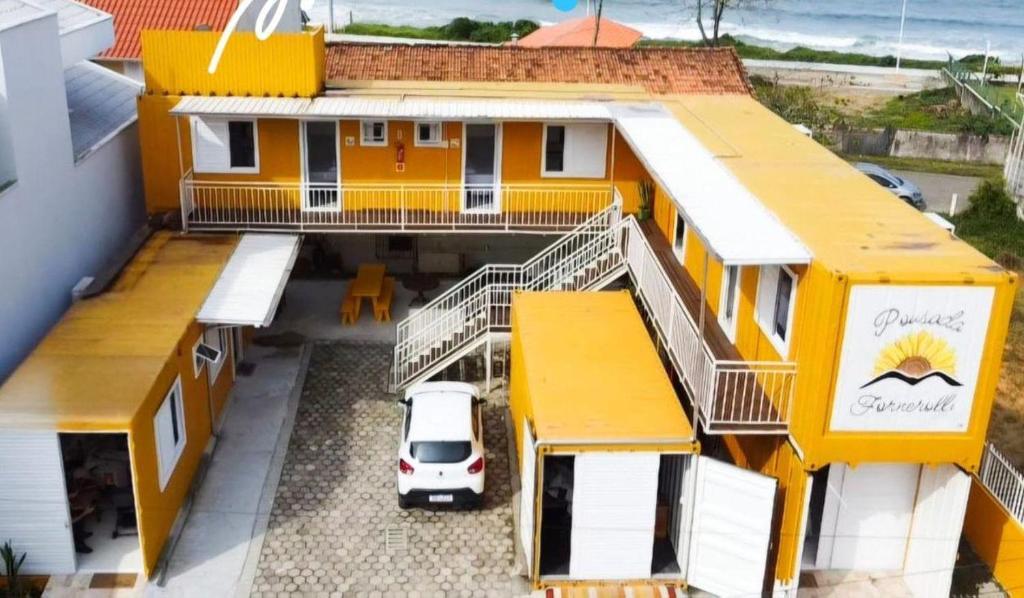 a yellow house with a white van parked in front of it at Pousada Fornerolli in Penha