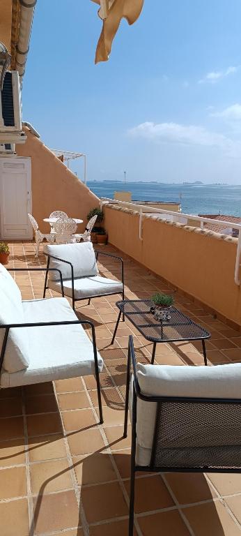 a balcony with chairs and tables and the ocean at Casa Doris in Los Alcázares