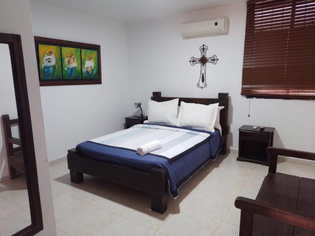 een slaapkamer met een bed met een kruis aan de muur bij Hotel La Casona Valledupar in Valledupar