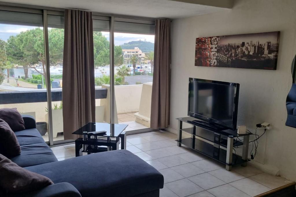 un salon avec un canapé bleu et une télévision dans l'établissement Naturiste Cap d'Agde Port Nature 544, au Cap d'Agde