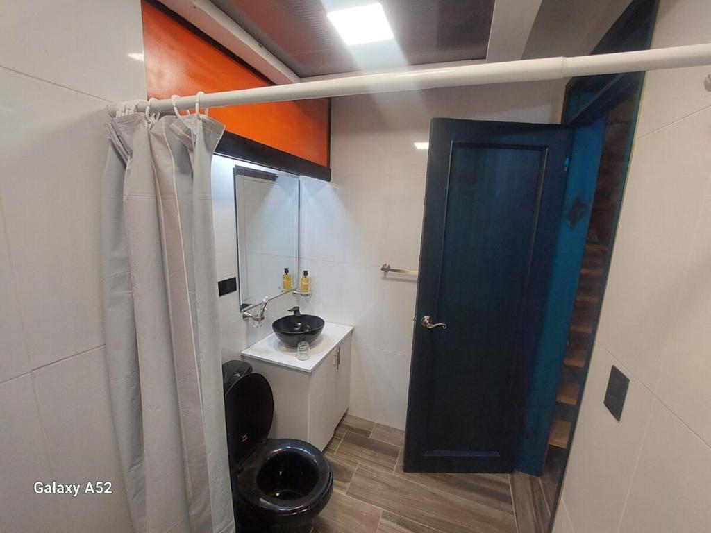baño con aseo y puerta negra en Private Casita near UIO airport, en Hacienda Otón
