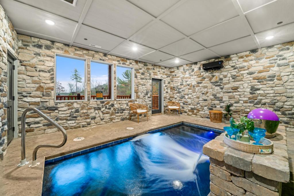 a swimming pool in a room with a stone wall at Indoor Pool Oasis, Hot Tub, EV, Scenic Views in Pigeon Forge