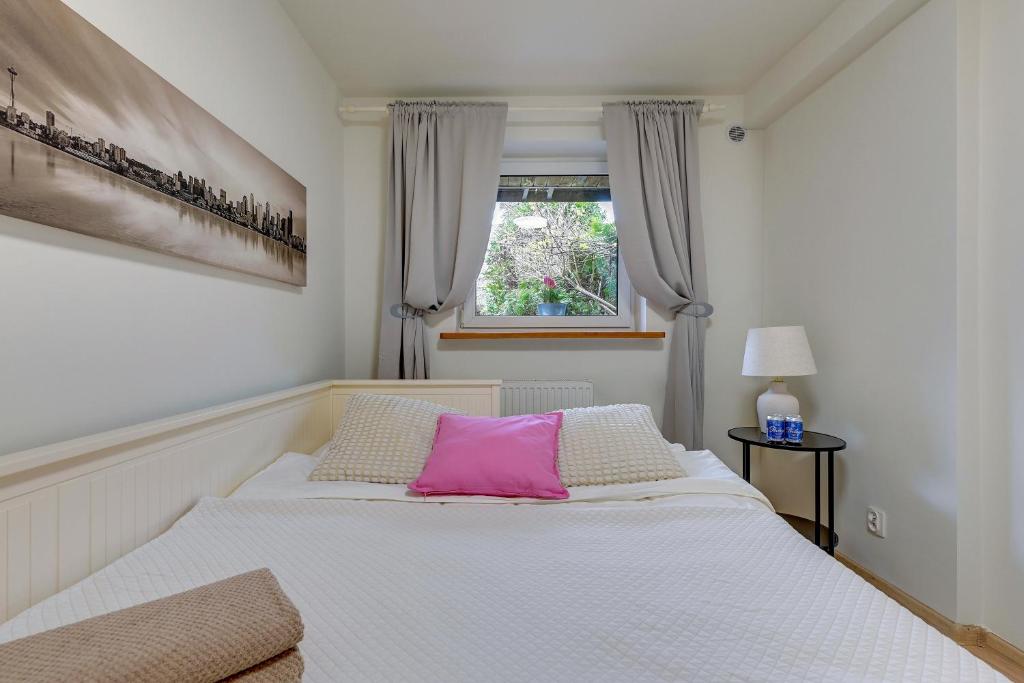 a bedroom with a white bed with a pink pillow at Apartament 48 in Gdańsk
