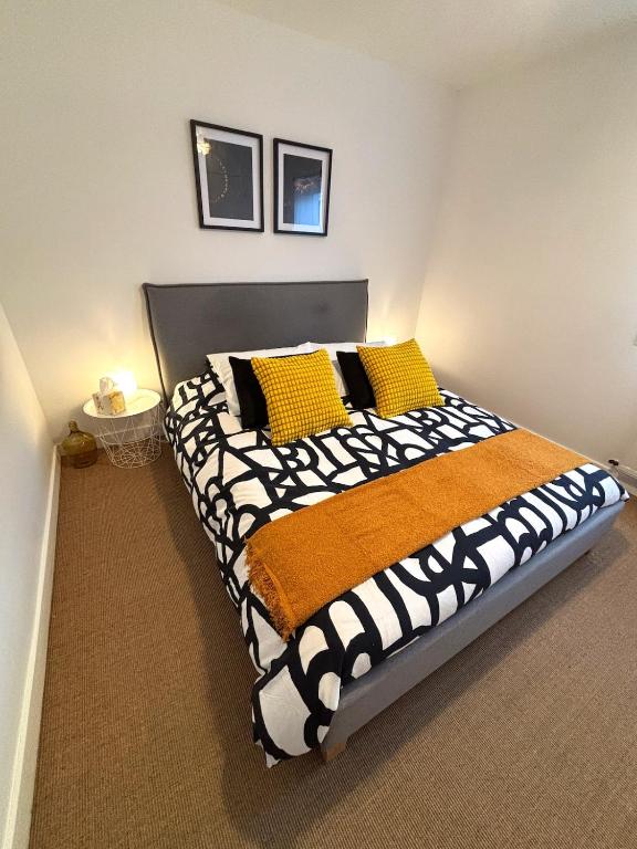 - une chambre dotée d'un grand lit avec des oreillers jaunes et noirs dans l'établissement Appartement avec parking à deux pas centre-ville et gare, à Saint-Brieuc
