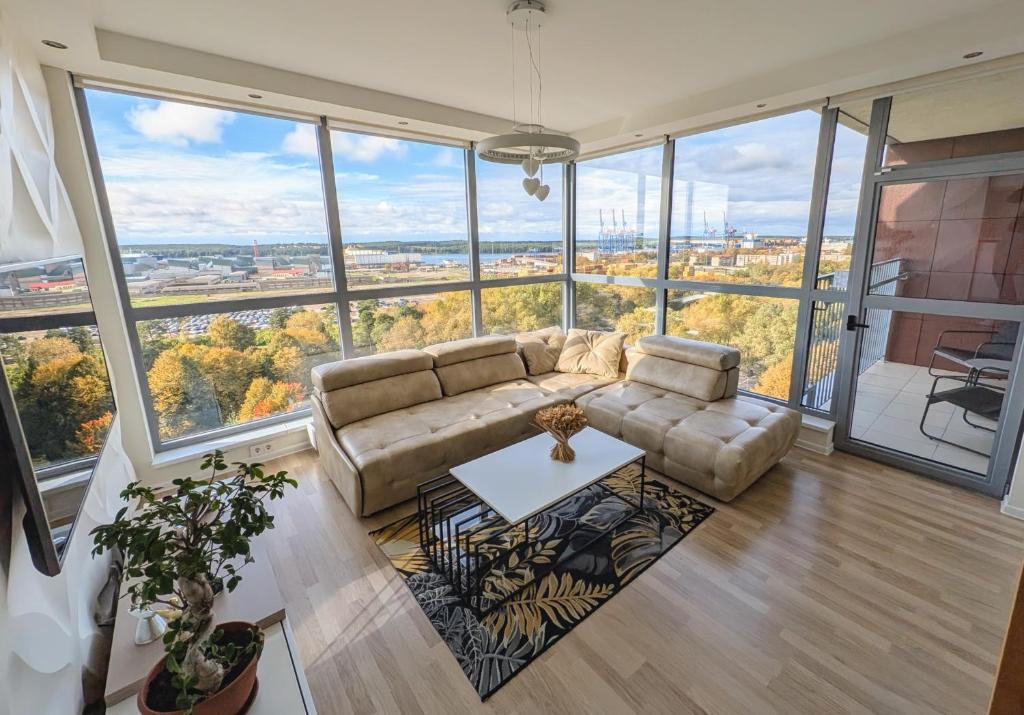een woonkamer met een bank en grote ramen bij White Dune Apartment - Self check-in in Klaipėda