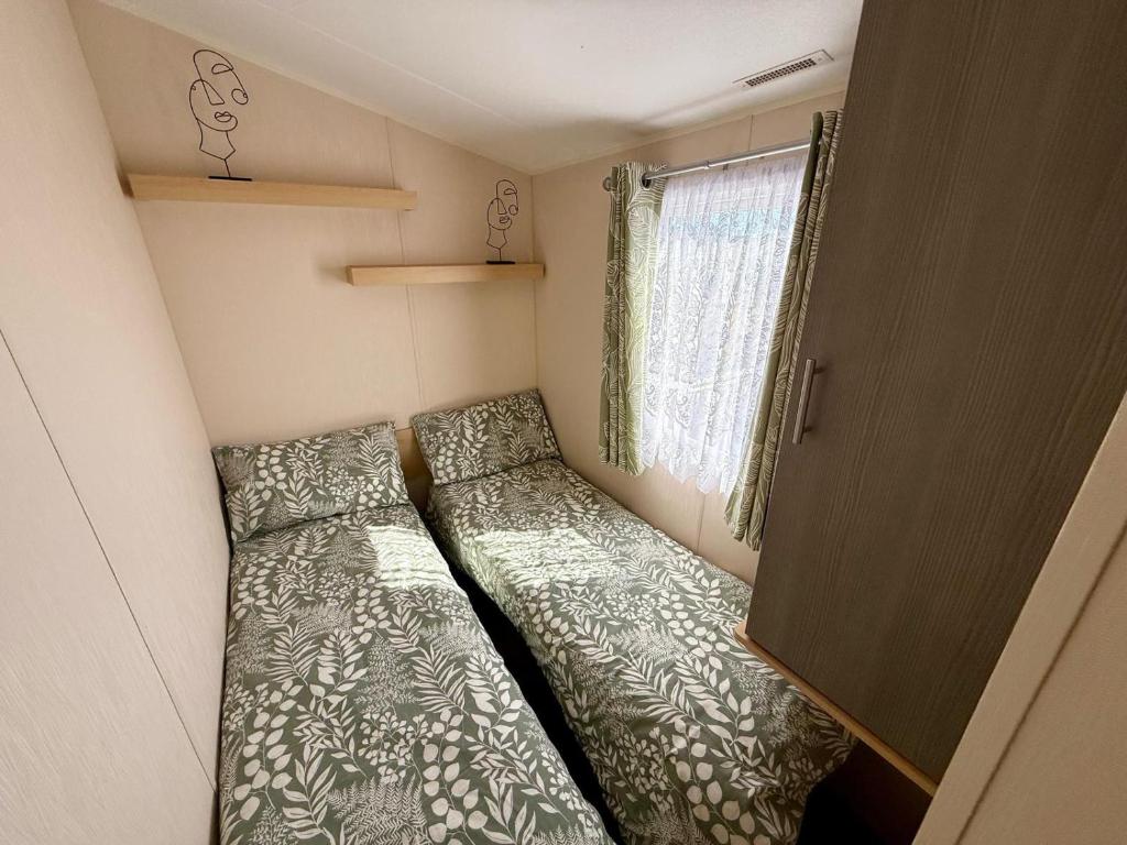a small room with two beds and a window at Poppys Place in Ingoldmells