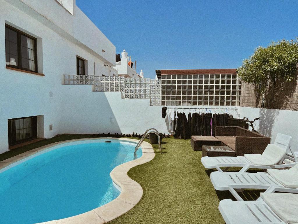 a swimming pool with white lounge chairs next to a building at Blue Surf House in Corralejo