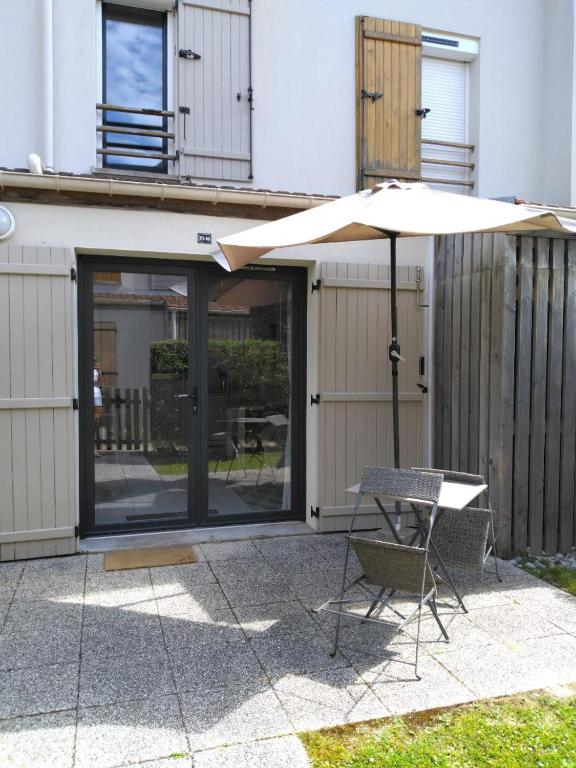 a table and an umbrella next to a building at Le lodge in Le Crotoy