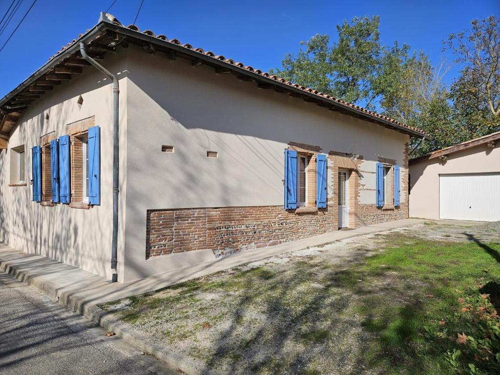 a house with blue windows and a driveway at La maisoun d'odette in Mérenvielle
