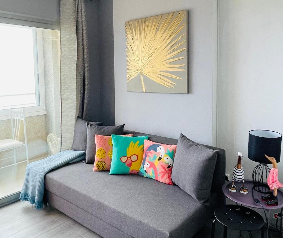 a living room with a gray couch with colorful pillows at Seafront Apartment with air conditioner in Empuriabrava