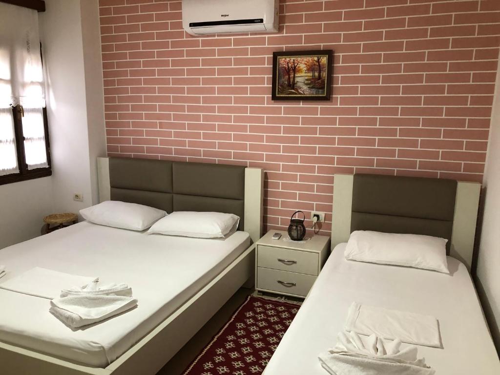 two beds in a room with a brick wall at Dhimitri's guest house in Berat