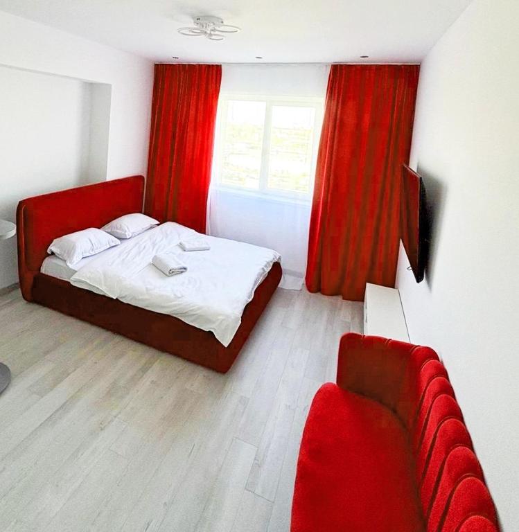 a bedroom with a bed with red curtains and a couch at Cataleya Luxury Room's in Bucharest