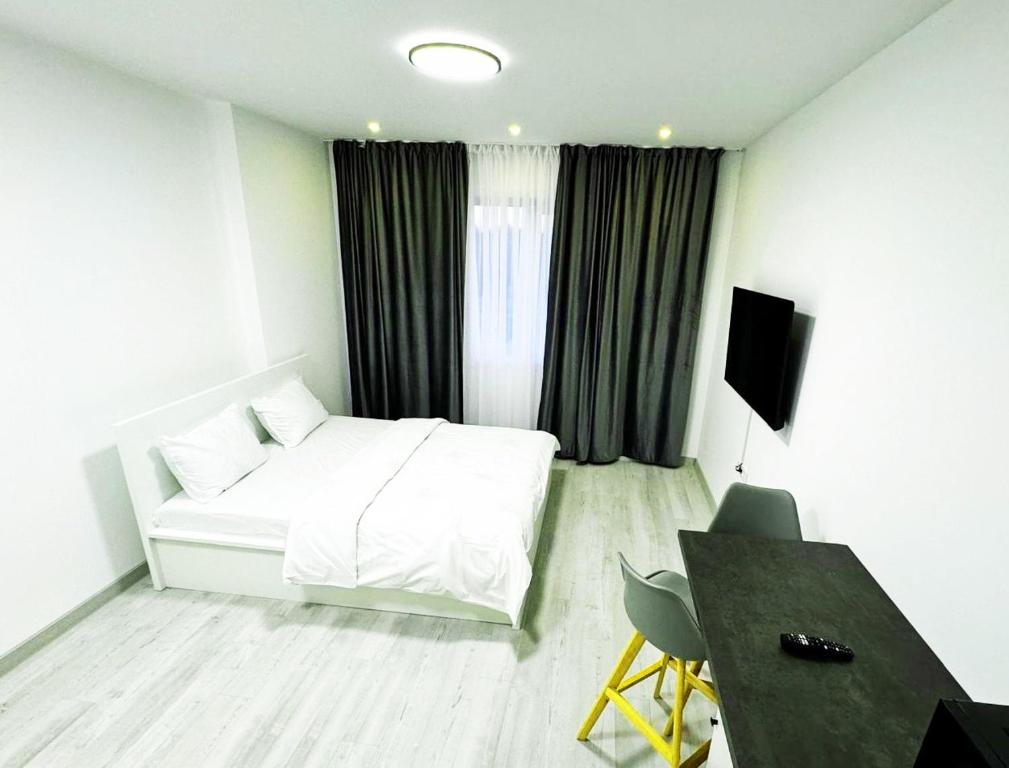 a hotel room with a white bed and a desk at Cataleya Suites Apartament's in Bucharest