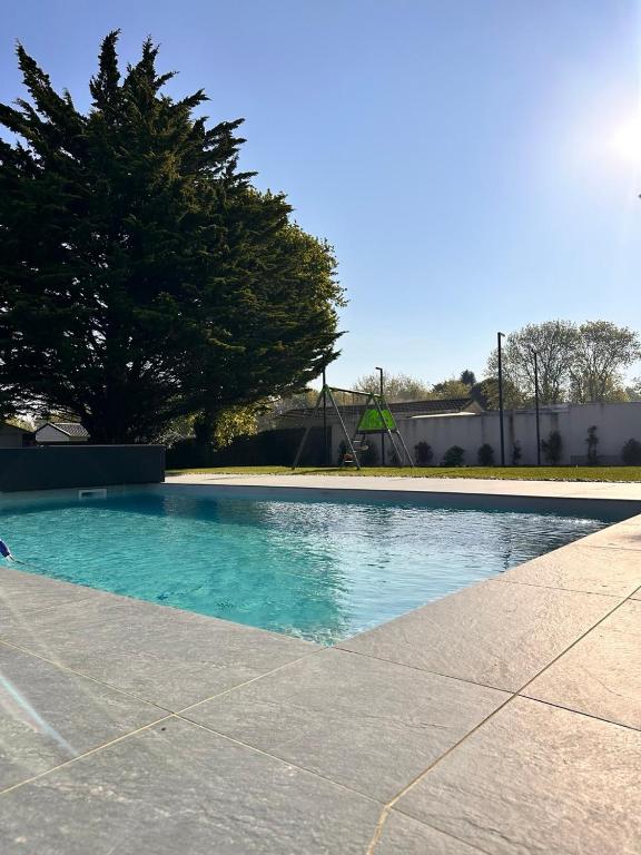 a swimming pool with blue water and a tree at Le Clos de la Côte Sauvage in Piriac-sur-Mer