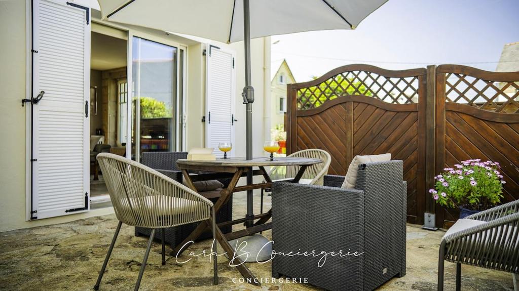 un patio avec une table, des chaises et un parasol dans l'établissement CORNOUAILLE house 6 p close to Concarneau beach, à Concarneau