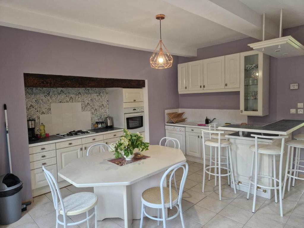a kitchen with a white table and white chairs at Maison à la campagne in Tollent