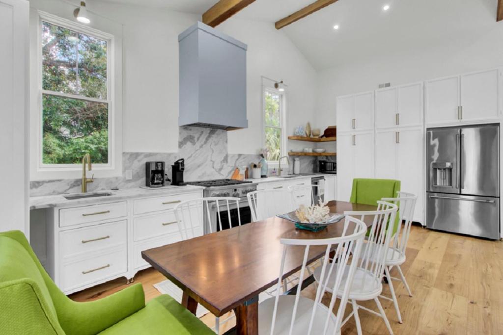 Una cocina con una mesa de madera y sillas verdes. en Sandcrab Court 22 by Wild Dunes, Luxury Home, en Isle of Palms
