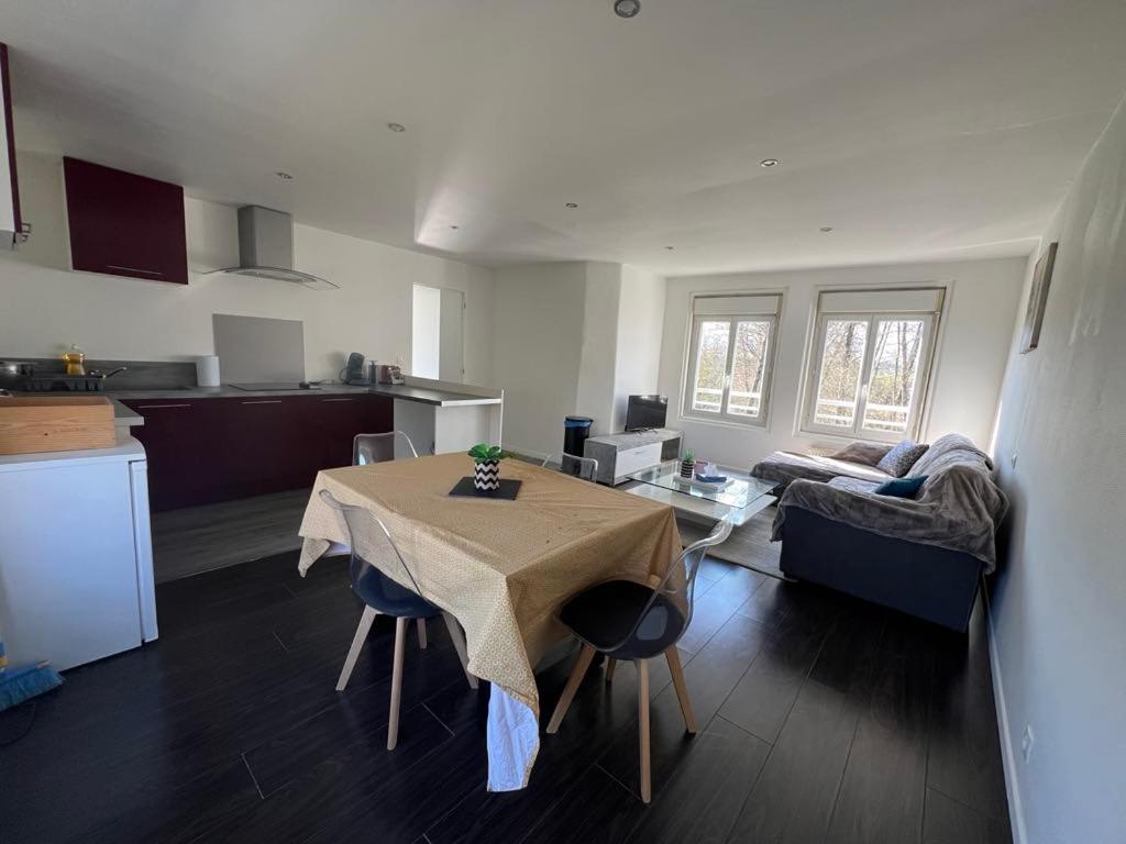 a kitchen and living room with a table and a couch at Appartement calme et paisible au bord de la rivière in Ernée