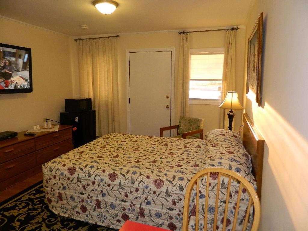 a bedroom with a bed and a dresser and a window at Twin Oaks Motel in Manasquan