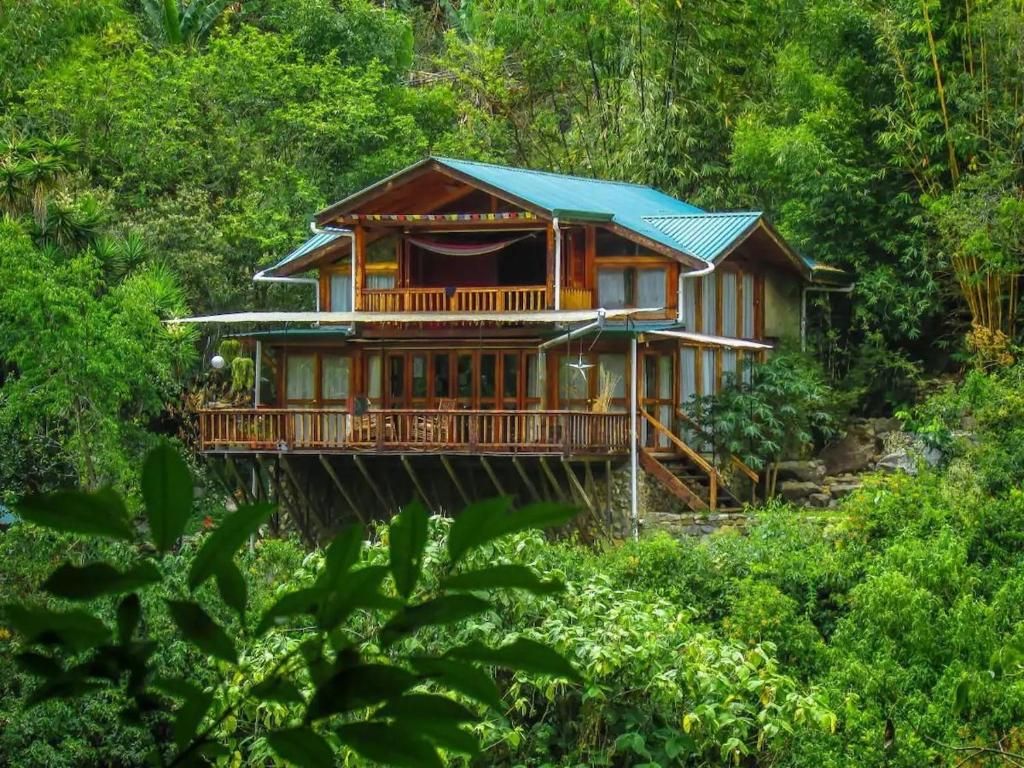a wooden house with a blue roof in the forest at Kubla Khan - Chirripó Mountain Riverfront Retreat in Rivas